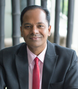 Closeup portrait of smiling middle-aged Indian business man looking at camera, working and sitting at cafe table