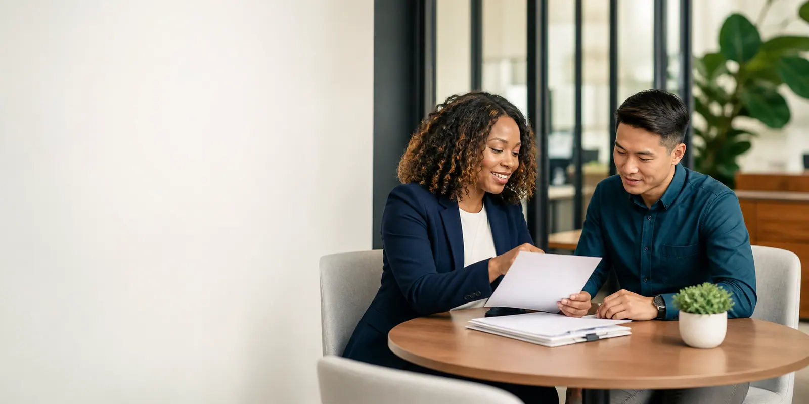 HR adviser going through employee paperwork with a colleague at a meeting table